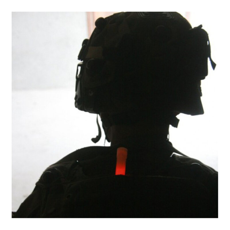 Militair in silhouet met helm en uitrusting, gemarkeerd door een rode Chemlight glowstick